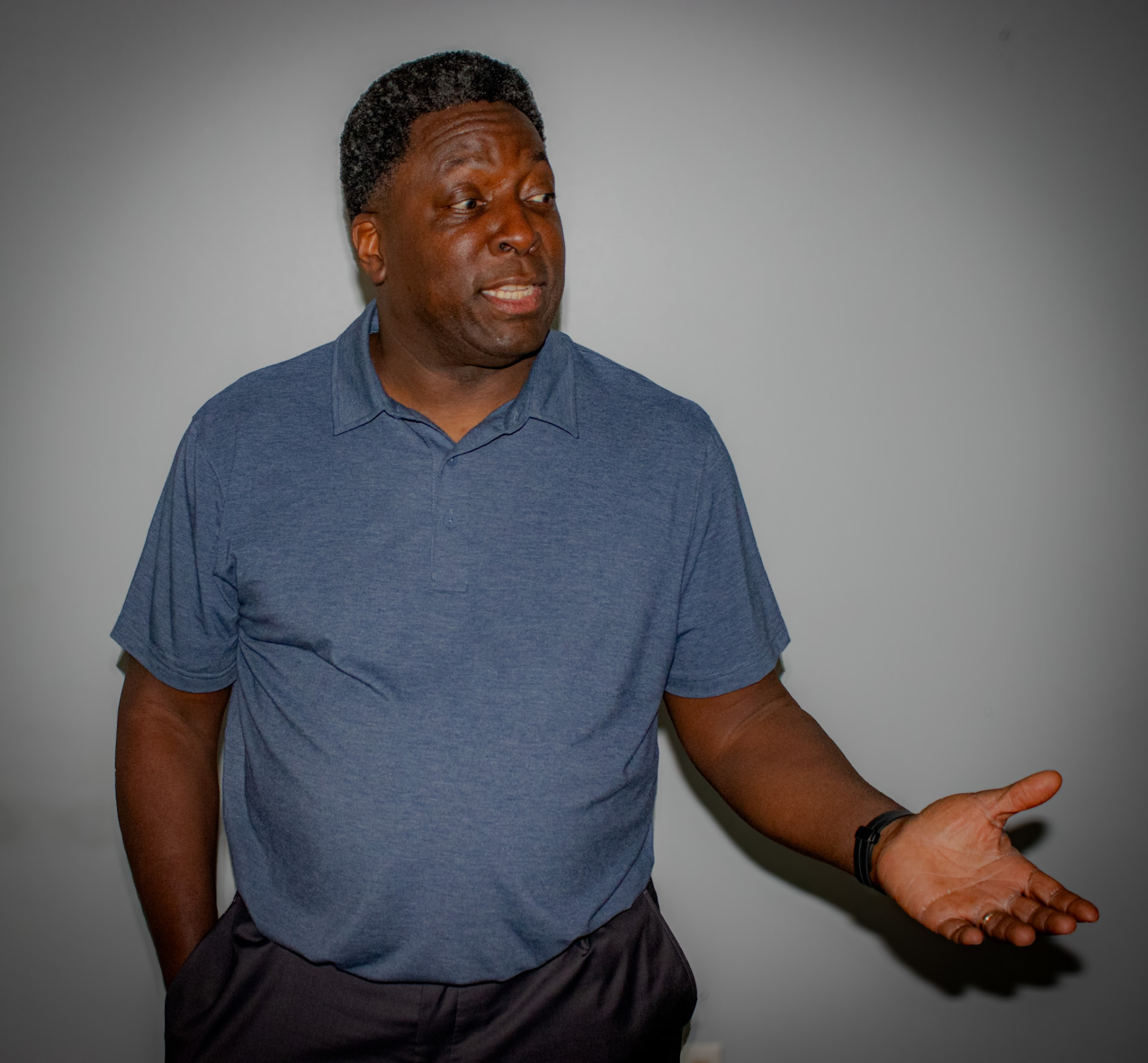 Dave London in a blue polo shirt, mid-conversation with one hand open in a gesture.