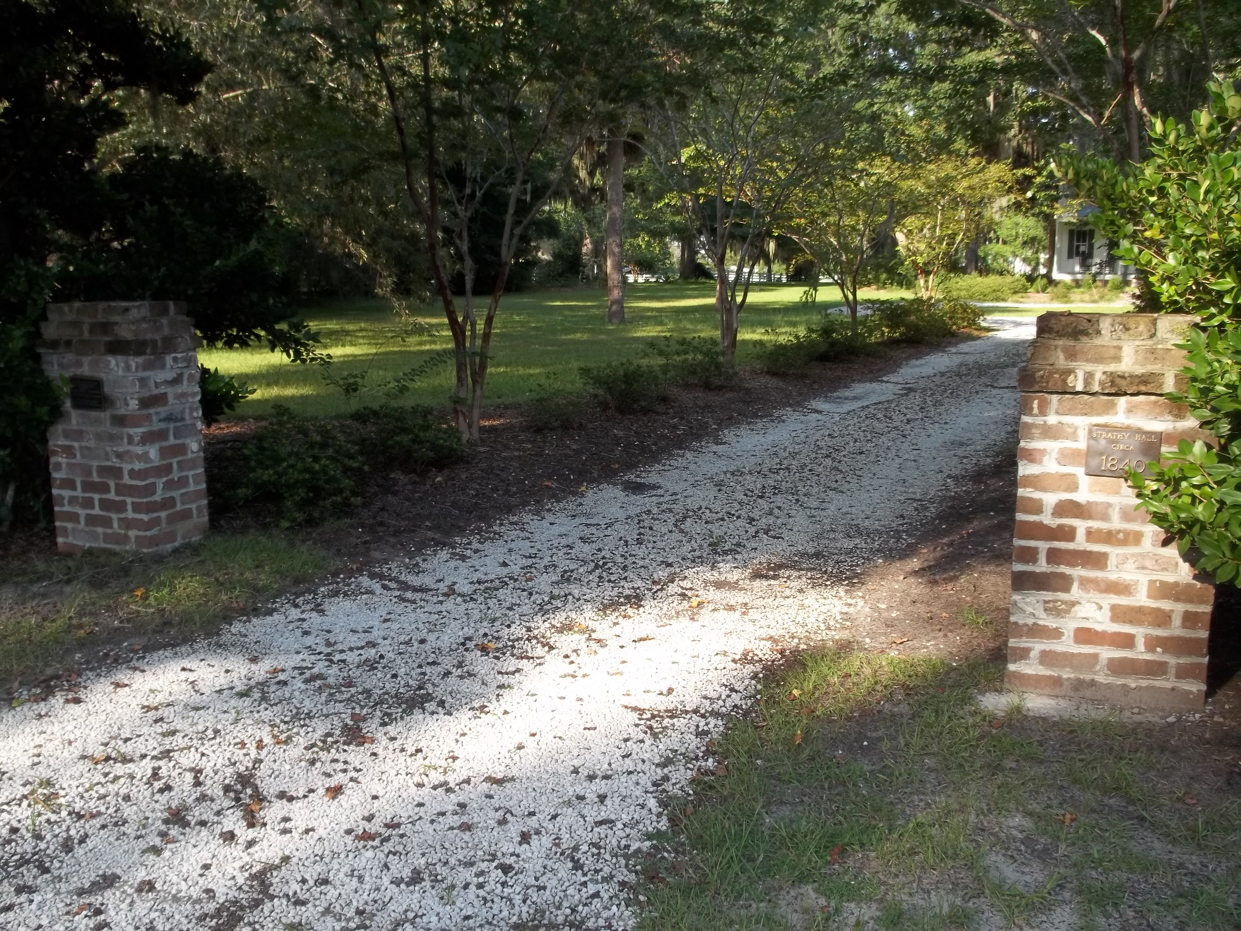 Brick entrance columns and a shaded, tree-lined drive at Strathy Hall in Richmond Hill, Bryan County, Georgia.